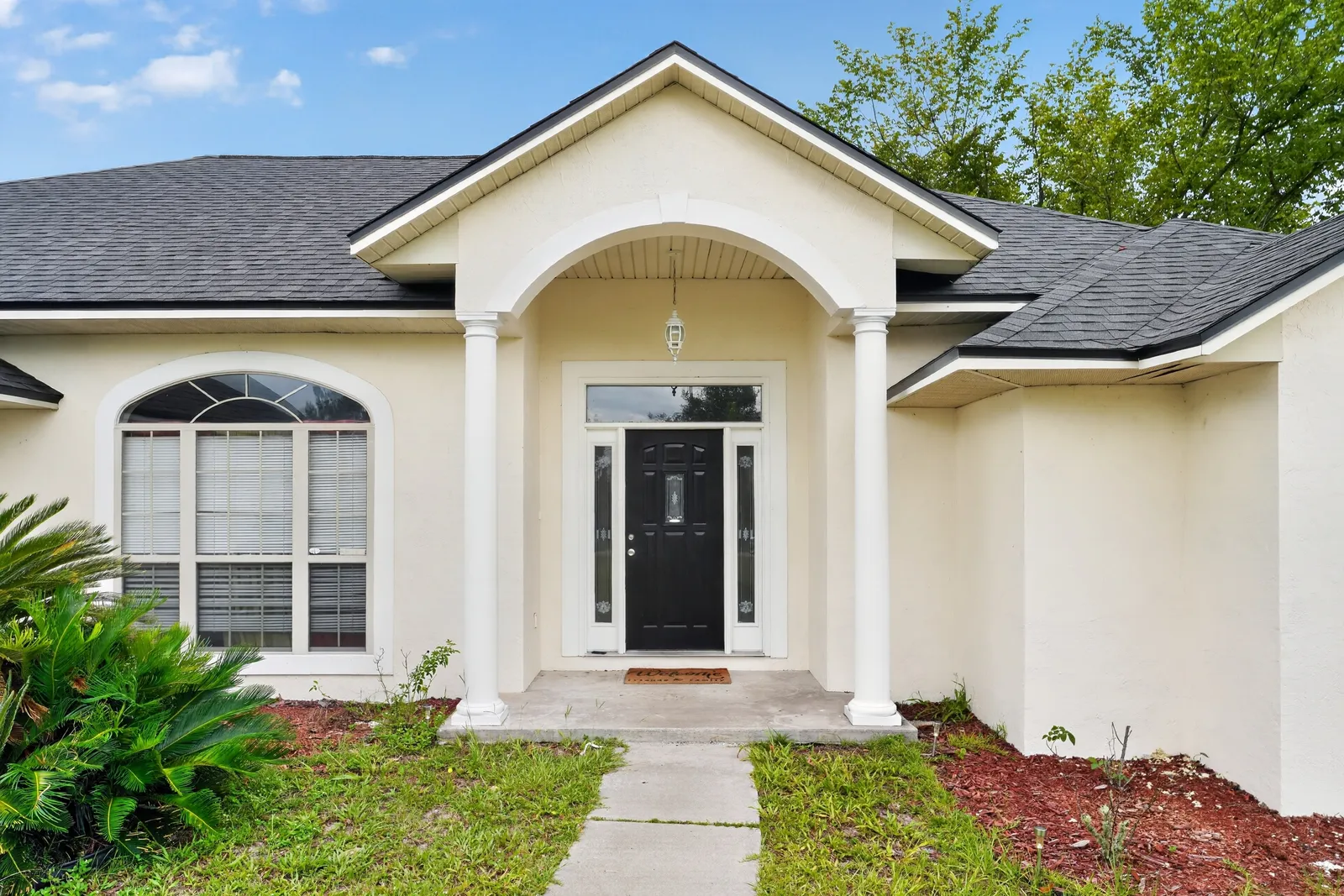 Stucco home with arched front entry and columns in Lake City