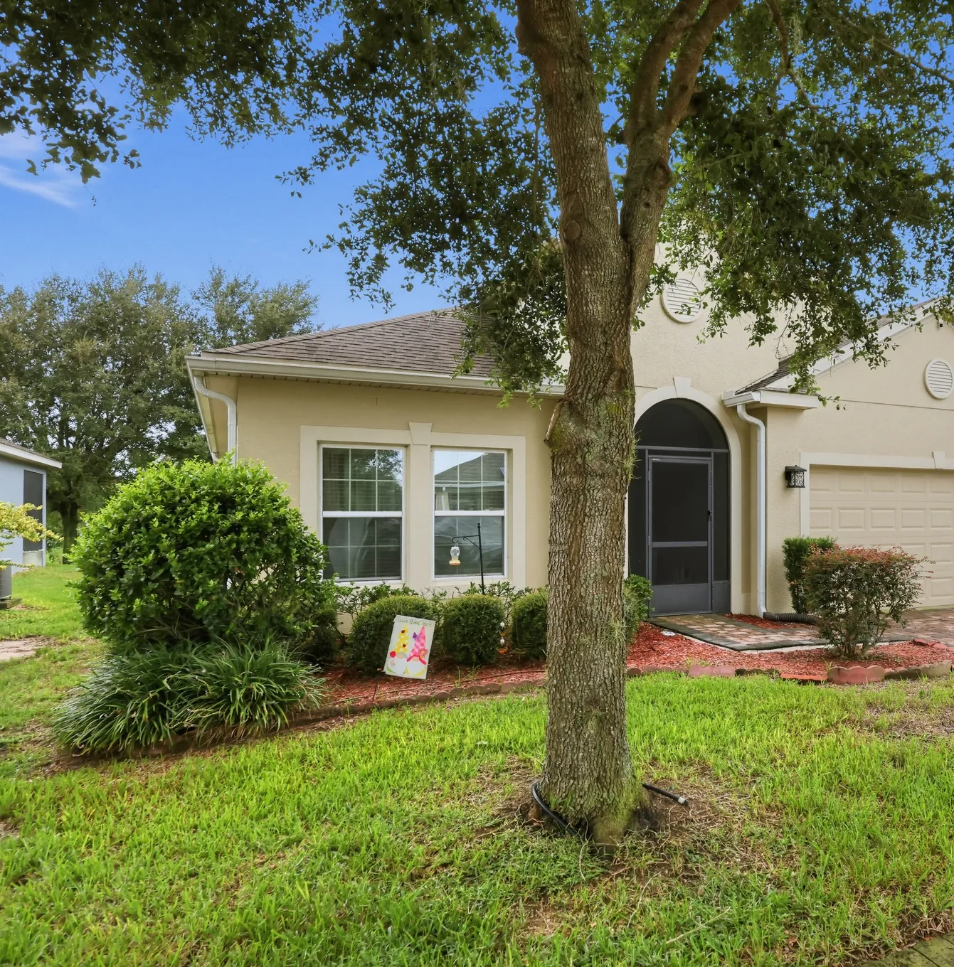 Stucco home with shade tree and arched entry in the Lake Wales area