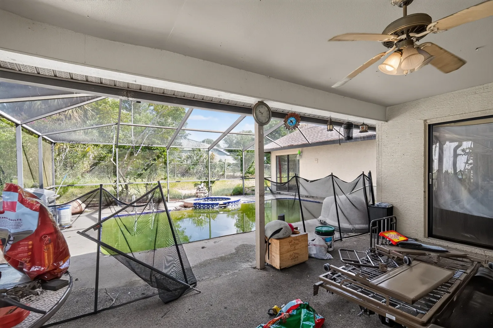 Screened lanai and a green, neglected pool at a Spring Hill home, as found before any repairs
